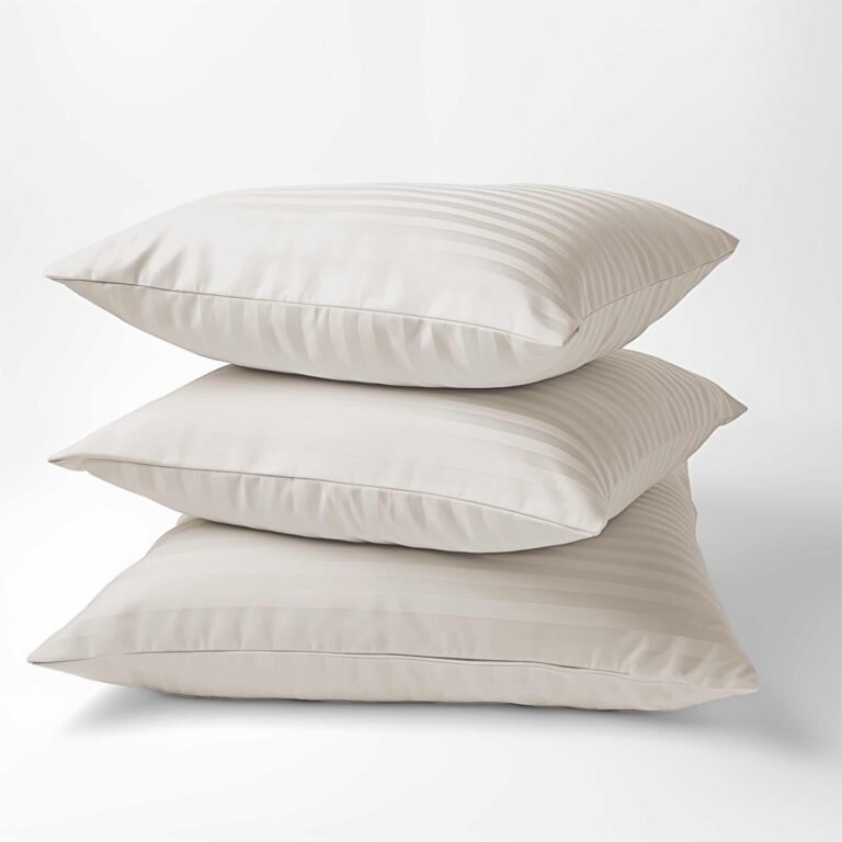 Zdjęcie przedstawiające Trzy poduszki w kolorze ecru ułożone w stos, wykonane z tkaniny o delikatnym wzorze w paski, przedstawione na białym tle